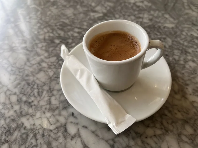 Eine Espressotasse und ein Zuckerpäckchen auf einer Marmortischplatte